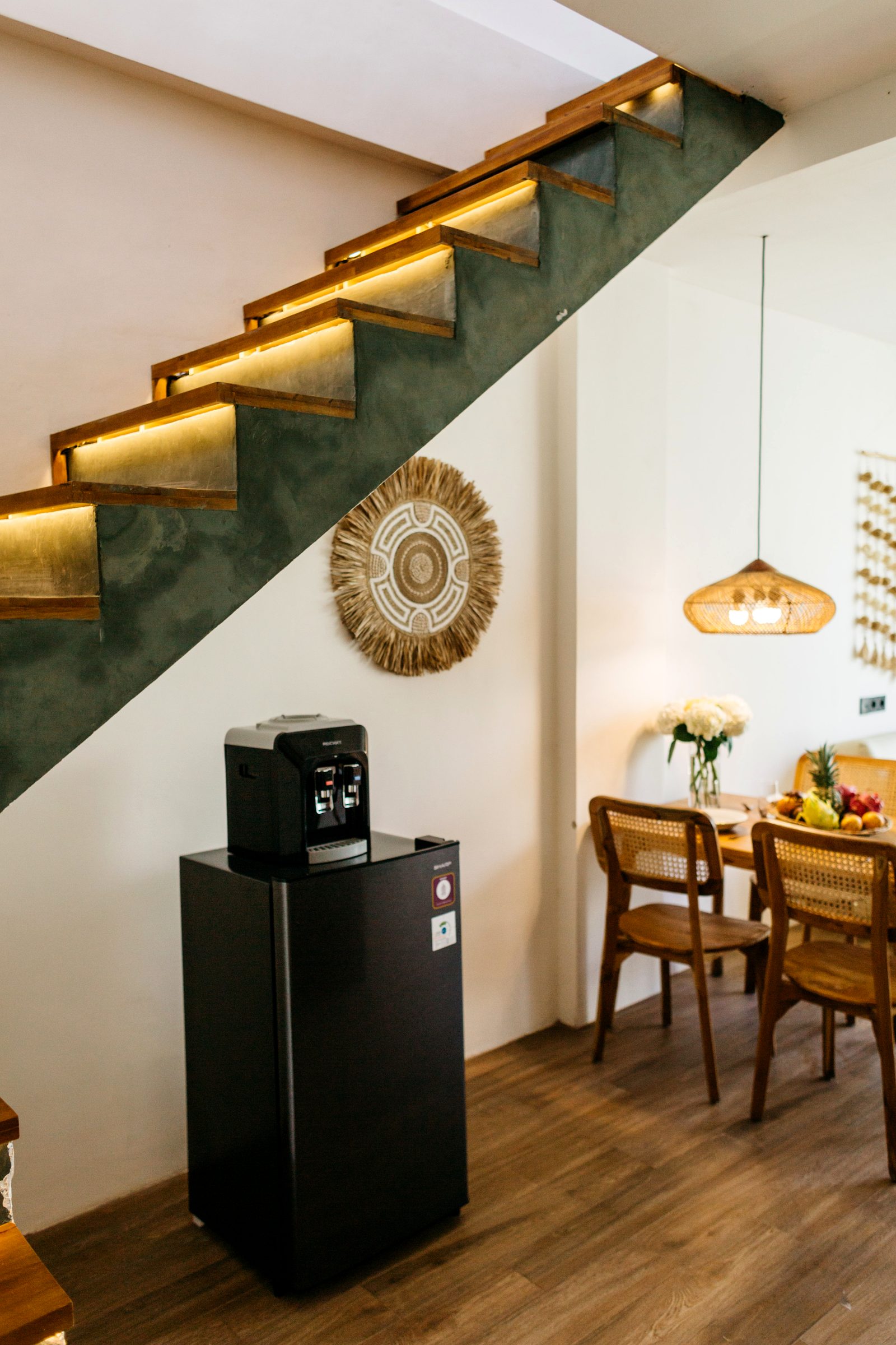 LED-lit teak staircase against green plaster — architectural detail, villa Ubud
