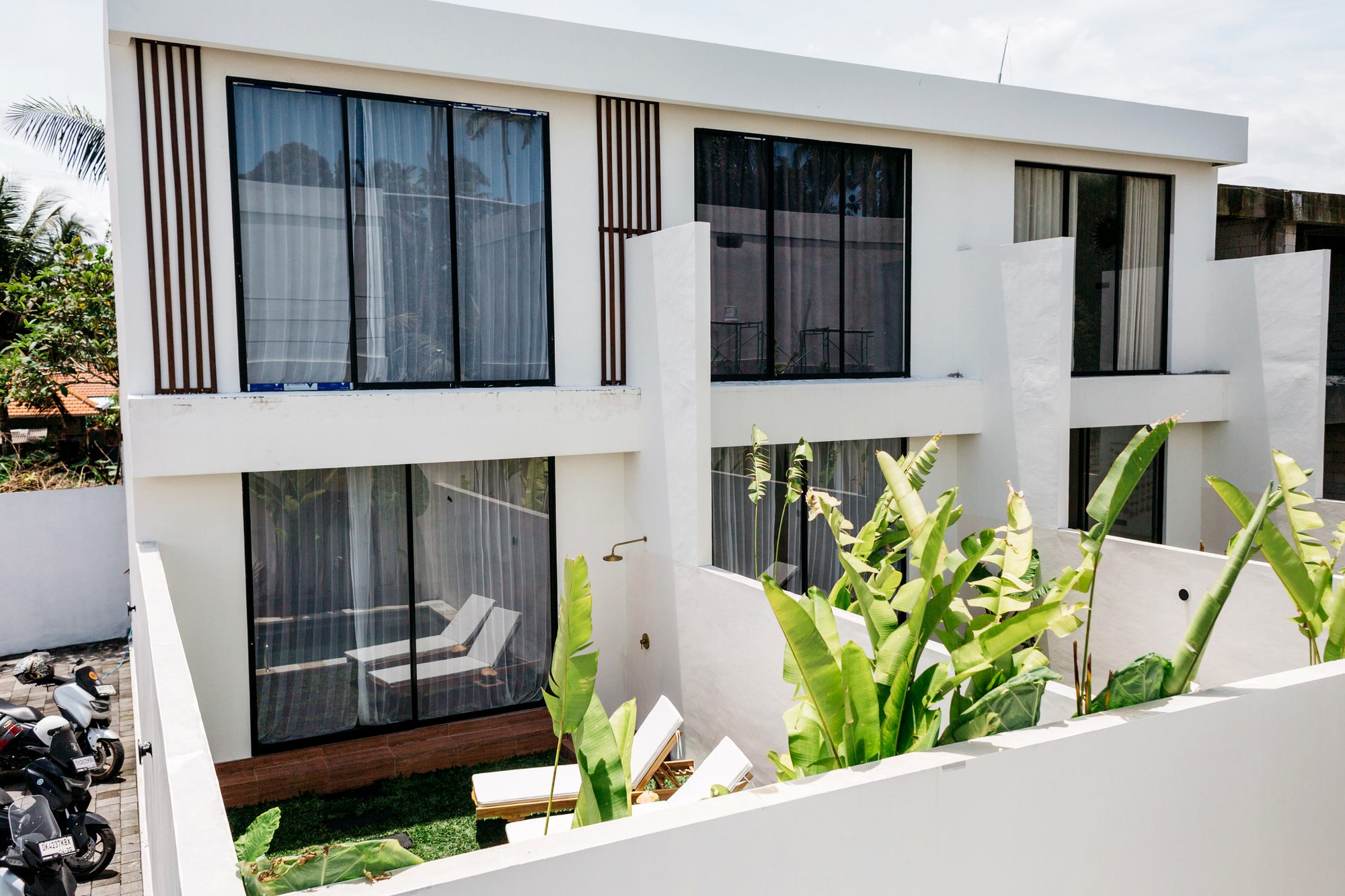 Two-storey white villa architecture with floor-to-ceiling glass and tropical planting — Santara Villas Resort, Singakerta Ubud